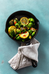 Poster - Top view fried brussels sprouts served in cast iron frying pan on blue stone background Healthy Vegetarian Food