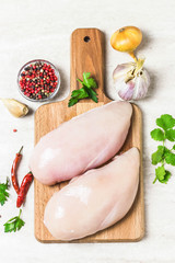 Fresh chicken fillet on cutting board with spices and herbs. Top view, space for text.