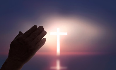 Concept of Jesus Christ: white cross on sunset sky background