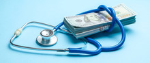 Stack Of Cash Dollars And Stethoscope On Blue Background. The Concept Of Medical Strechevka Or Expensive Medicine, Doctors Salary
