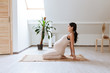 Pregnant woman stretching and training at home. Expectant female makes yoga exercise, healthy pregnancy concept