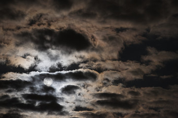 Wall Mural - full moon behind clouds in stormy sky.