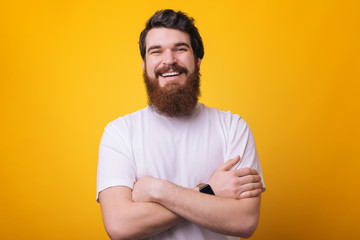 Wall Mural - Portrait of smiling man with beard in white shirt with crossed arms