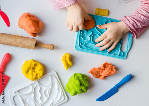 hands with colorful clay. Child playing