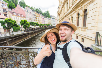 Wall Mural - Happy young couple in love takes selfie portrait in Karlovy Vary in Czech Republic. Pretty tourists make funny photos for travel blog in Europe