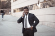 © SB Arts Media - Portrait of handsome african american businessman walking in the city talking on mobile phone