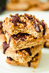 Granola bar cake with date caramel and chocolate. Healthy sweet dessert snack. Cereal granola bar with nuts, fruit and berries on a white marble table. Close-up.