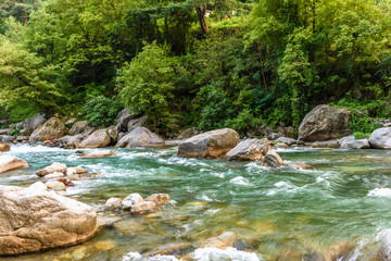 Landscape of the lush green Tirthan valley & the Tirthan river with turquoise water inside Great Himalayan National Park, India