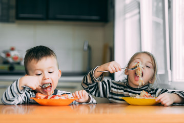 Wall Mural - Boy and girl in the kitchen eating pasta