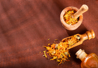 Wall Mural - Essential oil made from marigold on rustic table - Calendula officinalis