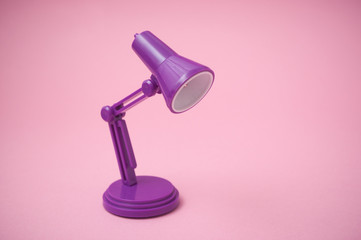 Closeup of mini purple modern lamp of desk on pink background