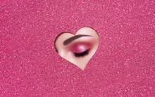 Conceptual Photo Of Valentine's Day. Eye Of Girl With Festive Pink Makeup. Paper Heart On A Pink Background. Love Symbols Valentines Day