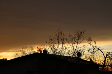 Alba con cielo rosso, silhouette della casa e degli alberi, panorama