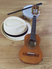 A samba player (sambista) hat and two Brazilian musical instruments: cavaquinho and tamborim with drumstick. The instruments are widely used to accompany samba, a popular Brazilian rhythm.