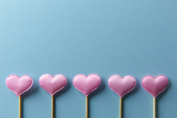 Pink textile hearts on wooden sticks closeup. Valentines day background, creative texture and love concept