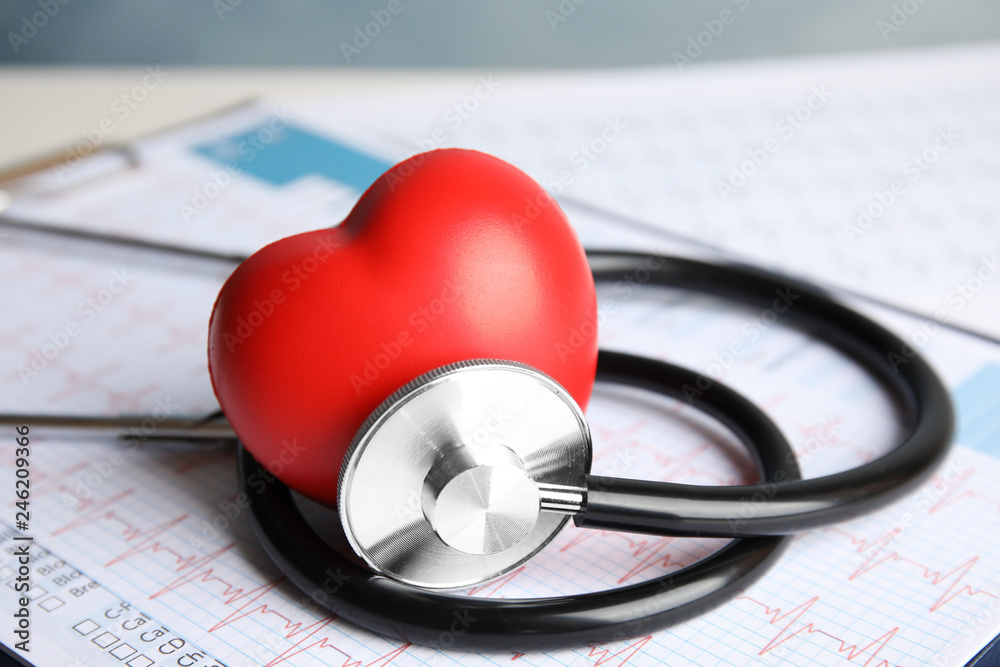 Stethoscope, red heart and cardiogram on table. Cardiology concept - obrazy, fototapety, plakaty 