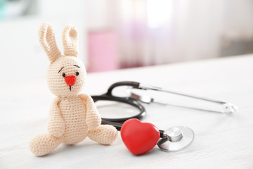 Wall Mural - Toy bunny, stethoscope and heart on table indoors, space for text. Children's doctor