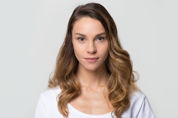 Head shot of young female with beautiful face, millennial woman looking at camera on white grey background, smiling pretty girl attractive model isolated against blank studio wall, portrait image