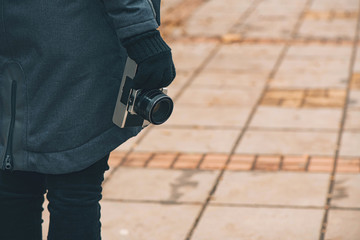 Hipster female photographer holding vintage SLR camera on street