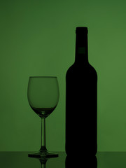 Wine glass and bottle on glossy black glass. Colorful background