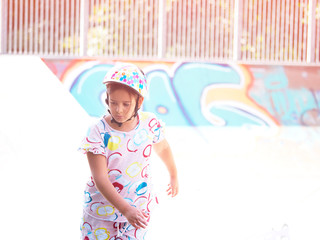 Little pretty girl on roller skates in helmet at a park