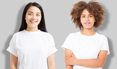Wall Mural - Asian and african american girl in blank template t shirt isolated on gray background. Women in tshirt with copy space and mock up for advertising. White shirts. Front view