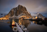 Fototapeta Góry - Hamnoy fishing village on Lofoten Islands at dawn. Norway with red rorbu houses in winter. A fishing boats at dawn in the fjord. Boats at the pier. Reine district