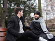 two young boys with beards sitting on a bench having a pleasant conversation, gay couple enjoying time together