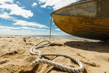 Old Fishing Boat With Rope On A Sandy Beach. Northern Authentic Seascape