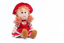 Soft Doll In A Red Dress And Hat On A White Background. Children's Toy. Close-up.