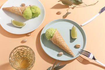 Wall Mural - Pistachio ice cream balls in waffle cones on a plate on a beige background. Top view.