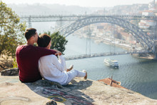 A Gay Couple Traveling And Enjoy Sunset Outdoor, European City View With Bridge And River