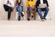 © Rithor - Freelance concept. Four young creative people work with gadgets sitting on chairs in large beautiful office - studio for co-working and outsourcing workers