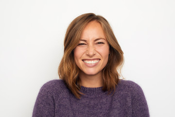 Wall Mural - portrait of a young happy woman smiling giggles on white background looking in camera