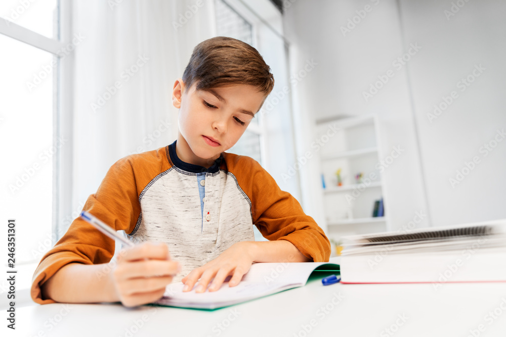 education, childhood and people concept - happy boy doing homework and ...