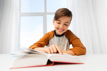 Wall Mural - education, childhood and people concept - happy student boy reading book at home