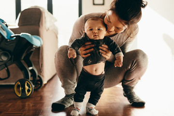 Wall Mural - Woman holding her baby squatting on floor