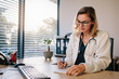 © Jacob Lund - Female doctor sitting at the desk and writing