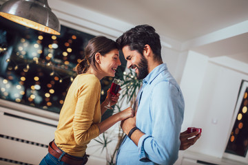 Portrait of a handsome man proposing to his happy girlfriend while holding engagement ring in a box