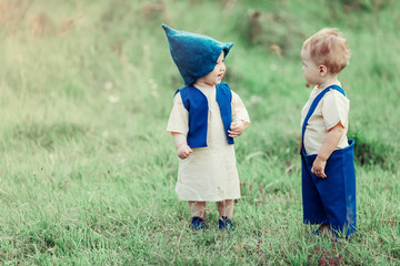 Wall Mural - Little infant cheerful caucasian baby boy and baby girl in gnome costume's together in forest. CHildhood, infant, adorable, fairy tale concept