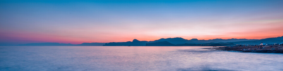 Wall Mural - Beautiful mysterious marine landscape at sunset. Mountains, volcanic reef and ocean, panoramic banner.