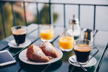 delicious breakfast with coffee, pastry, and orange juice served on the balcony with sea view.