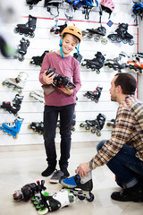 Wall Mural - male seller putting roller-skates on boy customer in sports store