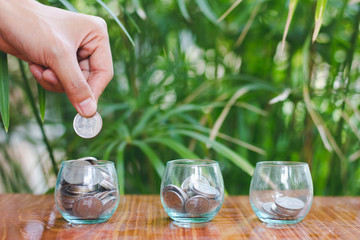 Woman's hand putting coin into glass of bottle for saving money, Saving money concept