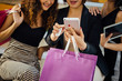 © Yingyaipumi - Beautiful girls are holding shopping bags, using a smart phone and smiling.shopping online concept.