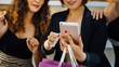 © Yingyaipumi - Beautiful girls are holding shopping bags, using a smart phone and smiling.shopping online concept.