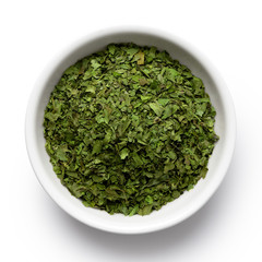 Wall Mural - Dried chopped coriander leaves in white ceramic bowl isolated on white from above.