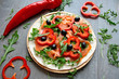 Tortilla smeared with horseradish sauce, covered with smoked salmon, rucola, paprika, and black olives