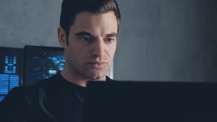 developer programmer working on computer in a data center filled with monitor screens. Steadicam shot