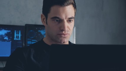 developer programmer working on computer in a data center filled with monitor screens. Steadicam shot